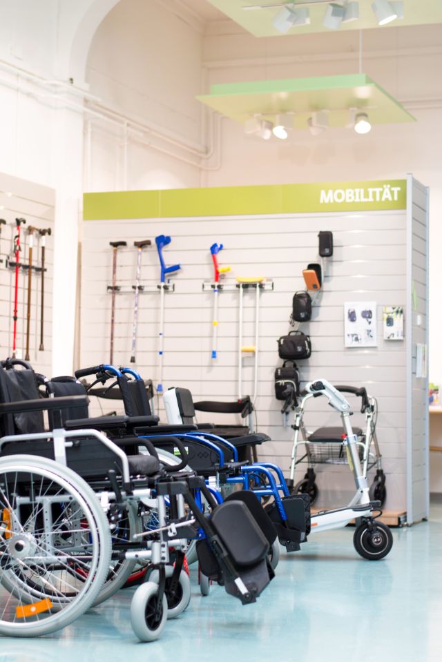 Ausstellungsraum mit Hilfsmitteln zur Bewahrung der Mobilität in Form von Rollstühlen und Gehhilfen.