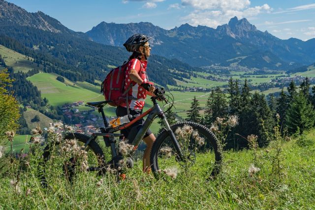 Eine ältere sportliche Frau geniesst den Ausblick während der eMountainbike Tour.