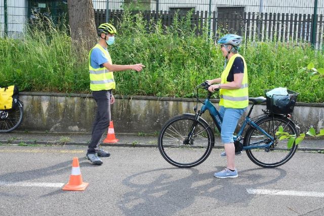 Ein Kursleiter eines E-Bike-Kurses erklärt einer Teilnehmerin wichtige Details zum Fahrverhalten.