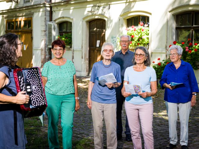 Eine Gruppe älterer Menschen singt draussen