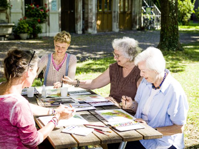 Ein Gruppe von Seniorinnen malt im Garten