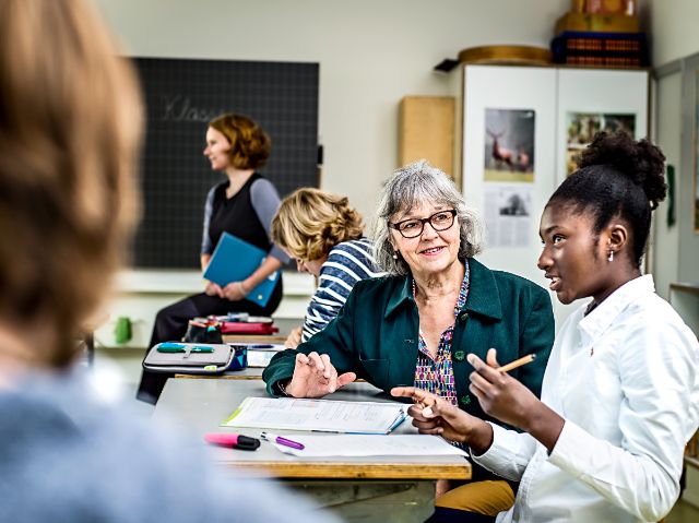 Eine Seniorin unterstützt ein Mädchen beim Lösen ihrer Mathematikaufgaben während des Unterrichts.